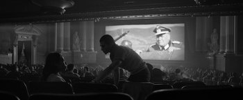 Movie still from “Roma” (2018), directed by Alfonso Cuarón – A man sitting in front of a screen in a movie theater; Wide shot, Low angle