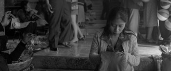 Movie still from “Roma” (2018), directed by Alfonso Cuarón – A woman sitting on the ground with a bag; Medium shot, High angle