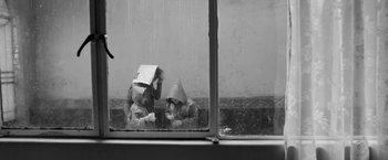 Movie still from “Roma” (2018), directed by Alfonso Cuarón – Two people sitting on a window ledge in the pouring rain; Wide shot, High angle