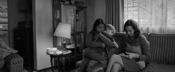 Movie still from “Roma” (2018), directed by Alfonso Cuarón – A woman sitting on a chair holding a child; Medium shot, High angle