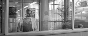 Movie still from “Roma” (2018), directed by Alfonso Cuarón – A woman standing behind a window looking out at a building; Medium shot, Over the shoulder angle