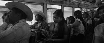 Movie still from “Roma” (2018), directed by Alfonso Cuarón – A man and a woman sitting on a bus next to another woman; Medium shot, High angle