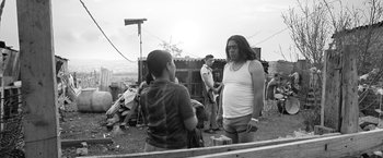Movie still from “Roma” (2018), directed by Alfonso Cuarón – A man with long black hair talking to a young boy; Medium shot, Over the shoulder angle