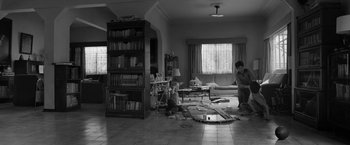 Movie still from “Roma” (2018), directed by Alfonso Cuarón – A black - and - white photo of a living room with a bookshelf; Wide shot, High angle