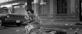Movie still from “Roma” (2018), directed by Alfonso Cuarón – A woman laughing while a man lies on the ground; Wide shot, Low angle