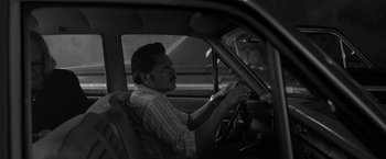Movie still from “Roma” (2018), directed by Alfonso Cuarón – An older man sitting in the driver's seat of a car; Medium shot, Over the shoulder angle