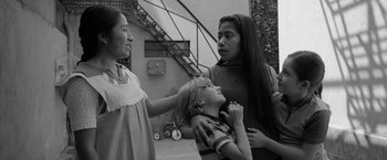 Movie still from “Roma” (2018), directed by Alfonso Cuarón – A woman and two children standing next to each other; Medium shot, Low angle