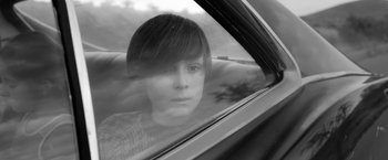 Movie still from “Roma” (2018), directed by Alfonso Cuarón – A young person sitting in a car looking out the window; Close Up shot, High angle