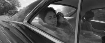 Movie still from “Roma” (2018), directed by Alfonso Cuarón – A woman sitting in a car with a young child; Close Up shot, Low angle