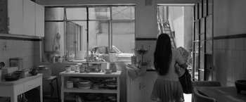 Movie still from “Roma” (2018), directed by Alfonso Cuarón – A woman standing in front of a window in a kitchen; Wide shot, Over the shoulder angle