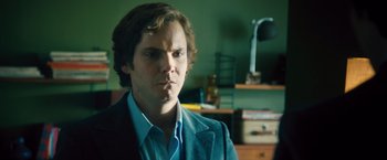 Movie still from “Rush” (2013), directed by Ron Howard – A man with long hair is looking at the camera; Close Up shot, Over the shoulder angle