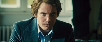 Movie still from “Rush” (2013), directed by Ron Howard – A person wearing a suit and tie; Close Up shot, Over the shoulder angle