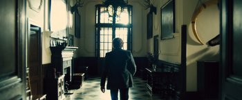 Movie still from “Rush” (2013), directed by Ron Howard – A woman in a suit walking in a hallway; Wide shot, Low angle