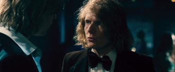 Movie still from “Rush” (2013), directed by Ron Howard – A man with blonde hair wearing a suit and a bow tie; Close Up shot, Over the shoulder angle