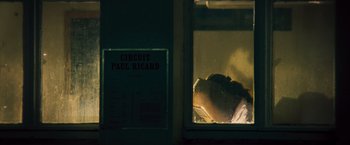 Movie still from “Rush” (2013), directed by Ron Howard – A person laying in a dark room looking out of a window; Medium shot, Low angle