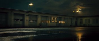 Movie still from “Rush” (2013), directed by Ron Howard – A street light shines in the dark on a rainy night; Extreme Wide shot, Low angle