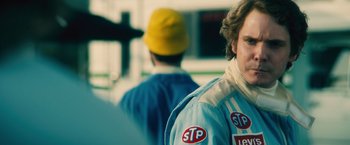 Movie still from “Rush” (2013), directed by Ron Howard – A person wearing a racing suit; Close Up shot, Over the shoulder angle