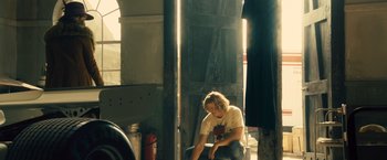 Movie still from “Rush” (2013), directed by Ron Howard – A person sitting on a chair in a room; Medium shot, Low angle