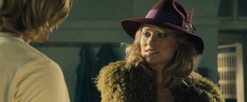 Movie still from “Rush” (2013), directed by Ron Howard – A woman wearing a purple hat and a fur coat; Close Up shot, Over the shoulder angle