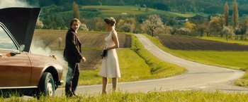 Movie still from “Rush” (2013), directed by Ron Howard – A man and a woman standing next to each other on the side of a road; Wide shot, Over the shoulder angle