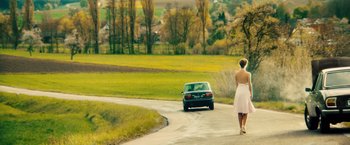 Movie still from “Rush” (2013), directed by Ron Howard – A woman walking down a road next to a car; Wide shot, Low angle