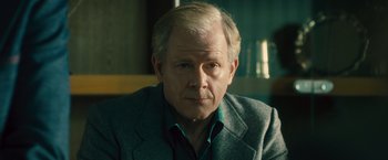 Movie still from “Rush” (2013), directed by Ron Howard – An older man in a gray jacket and green shirt; Close Up shot, Over the shoulder angle