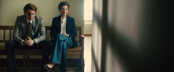 Movie still from “Rush” (2013), directed by Ron Howard – A woman sitting on a wooden chair in a room; Medium shot, Low angle