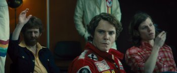 Movie still from “Rush” (2013), directed by Ron Howard – A man in a red and white racing suit; Close Up shot, Over the shoulder angle