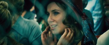 Movie still from “Rush” (2013), directed by Ron Howard – A beautiful young lady wearing a hat and posing for a picture; Close Up shot, Over the shoulder angle