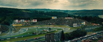 Movie still from “Rush” (2013), directed by Ron Howard – A large crowd of people watching a race on a track; Extreme Wide shot, High angle