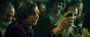 Movie still from “Rush” (2013), directed by Ron Howard – A woman is looking into the distance while a group of people are watching; Close Up shot, Over the shoulder angle