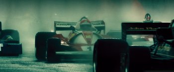 Movie still from “Rush” (2013), directed by Ron Howard – A blurry image of a race car in a garage; Wide shot, Low angle