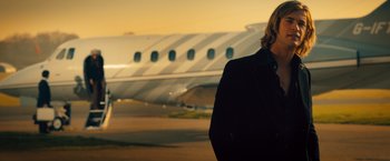 Movie still from “Rush” (2013), directed by Ron Howard – A man standing in front of a plane on a runway; Medium shot, Low angle
