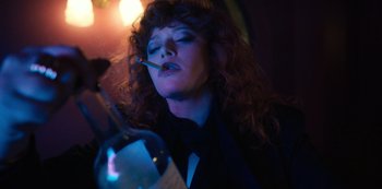 Movie still from “Russian Doll” (2019), created by Natasha Lyonne – A woman smoking a cigarette while holding a bottle of wine; Medium shot, Low angle