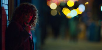 Movie still from “Russian Doll” (2019), created by Natasha Lyonne – A woman with curly red hair standing on a street at night; Medium shot, Over the shoulder angle