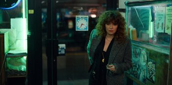 Movie still from “Russian Doll” (2019), created by Natasha Lyonne – A woman standing next to a building holding a cell phone; Medium shot, Over the shoulder angle