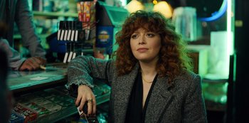 Movie still from “Russian Doll” (2019), created by Natasha Lyonne – A woman with curly hair and a black jacket holding a cell phone; Close Up shot, Over the shoulder angle