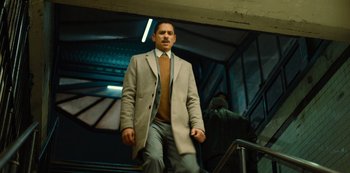 Movie still from “Russian Doll” (2019), created by Natasha Lyonne – A man wearing a coat and tie walking down a flight of stairs; Medium shot, Low angle