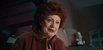 Movie still from “Russian Doll” (2019), created by Natasha Lyonne – An older woman smoking a cigarette in a room; Close Up shot, Low angle