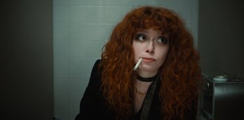 Movie still from “Russian Doll” (2019), created by Natasha Lyonne – A woman with red curly hair is smoking a cigarette; Close Up shot, High angle