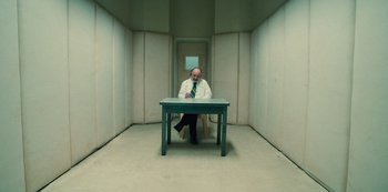 Movie still from “Russian Doll” (2019), created by Natasha Lyonne – A man sitting at a table in an empty room; Wide shot, High angle