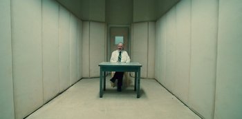 Movie still from “Russian Doll” (2019), created by Natasha Lyonne – A man sitting at a table in a room; Wide shot, High angle