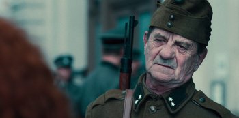 Movie still from “Russian Doll” (2019), created by Natasha Lyonne – An old man dressed in a uniform with a rifle; Close Up shot, Over the shoulder angle