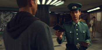 Movie still from “Russian Doll” (2019), created by Natasha Lyonne – A man in a green uniform is holding a wallet; Medium shot, Over the shoulder angle