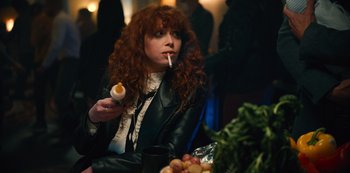 Movie still from “Russian Doll” (2019), created by Natasha Lyonne – A woman sitting at a table smoking a cigarette; Medium shot, Over the shoulder angle