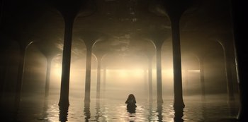Movie still from “Russian Doll” (2019), created by Natasha Lyonne – A person in a body of water surrounded by pillars; Extreme Wide shot, High angle