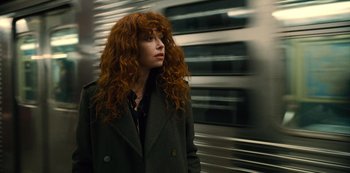 Movie still from “Russian Doll” (2019), created by Natasha Lyonne – A woman with long red curly hair standing in front of a train; Close Up shot, Low angle
