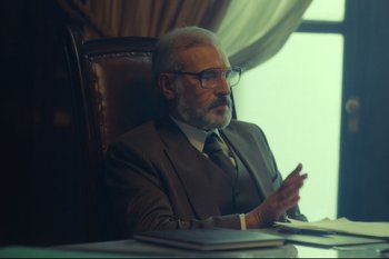 Movie still from “Argentina, 1985” (2022), directed by Santiago Mitre – An older man sitting at a desk in a suit and tie; Medium shot, Over the shoulder angle