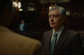Movie still from “Argentina, 1985” (2022), directed by Santiago Mitre – An older man wearing a suit and tie in a courtroom; Medium shot, Over the shoulder angle