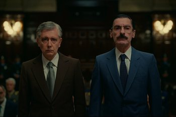 Movie still from “Argentina, 1985” (2022), directed by Santiago Mitre – A couple of men standing next to each other in suits; Medium shot, Low angle